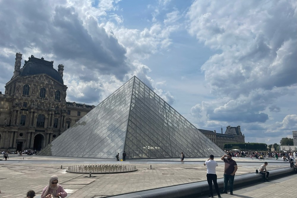 The glass pyramid at the Louvre under a dramatic sky, photographed by Michael Olaiya in 2023